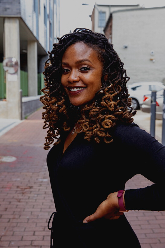 Smiling Woman in Black Dress with Curly Hair Outdoors